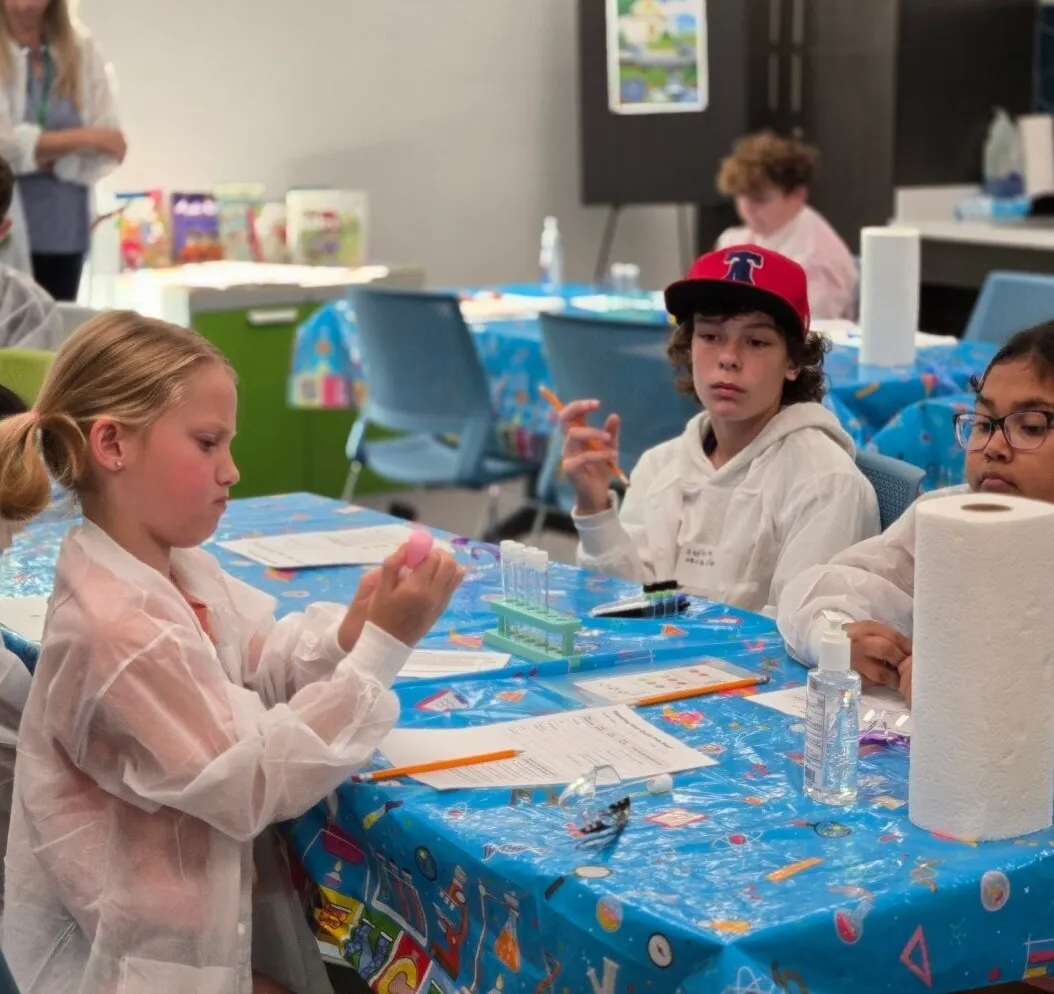 A Brainstorms educator helps a student with an activity during a library program